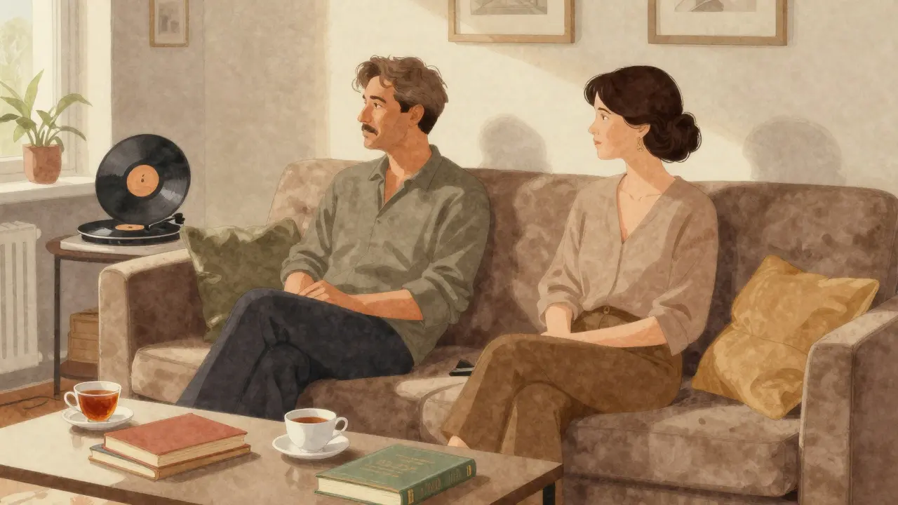 Two people sit quietly together on a sofa in a sunlit Berlin apartment, sharing tea and silence.